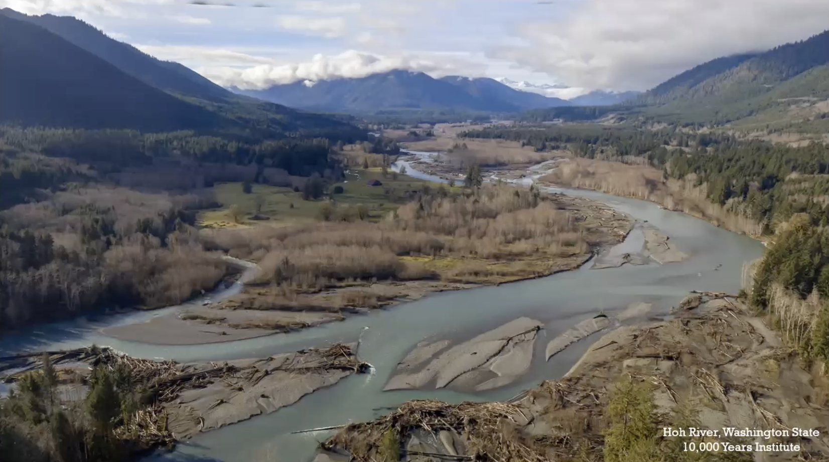 An aerial picture of the Hoh River, with mountains in the background, attributed to the 10,000 Years Institute.