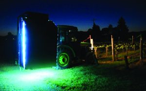A tractor mounted with with UV-C lights next to a vineyards.